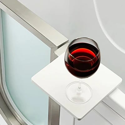 Red wine glass resting on a white swivel tray attached to an Ella walk-in tub with stainless steel frame