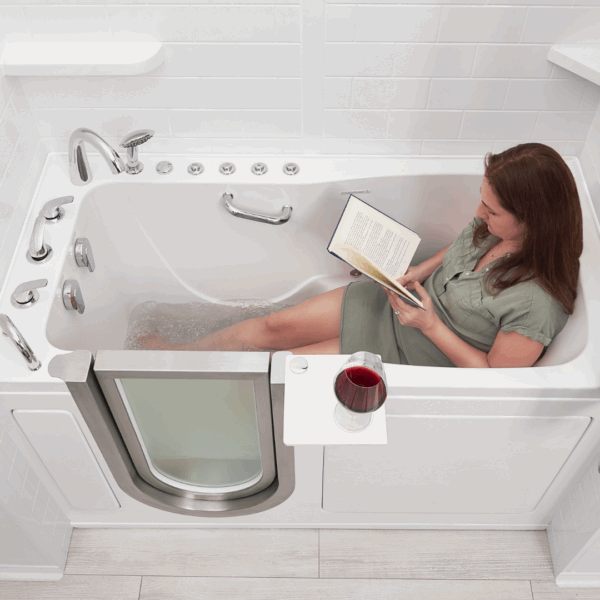 Woman relaxing in an Ella walk-in tub reading a book with a glass of red wine on the side tray