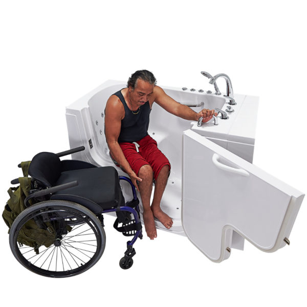 Wheelchair user transferring onto the wide seat of an Ella Transfer walk-in bathtub with open door beside his wheelchair