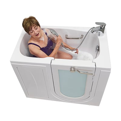 Senior woman in purple swimsuit using a handheld showerhead while soaking in an Ella walk-in tub with frosted side door