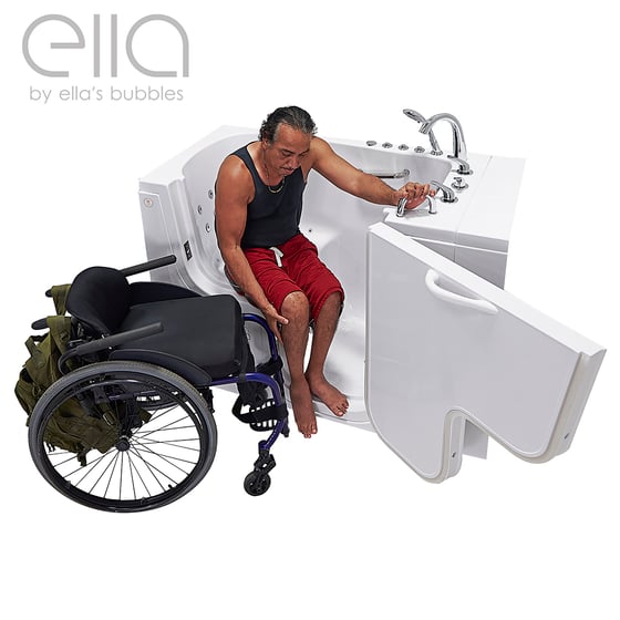 Usuario de silla de ruedas transfiriéndose hacia la bañera de acceso Ella Transfer con puerta ancha abierta y jets de hidromasaje junto a su silla de ruedas