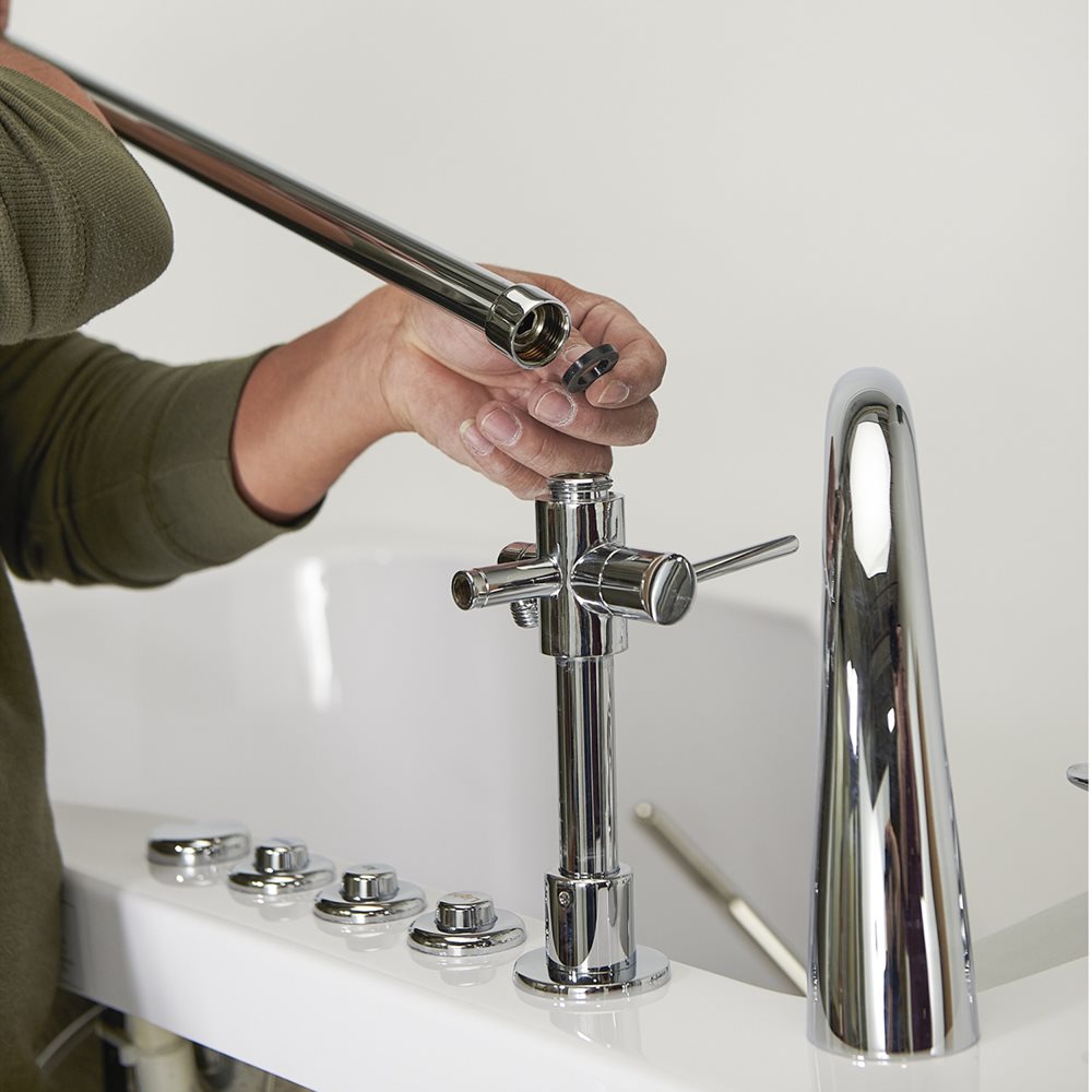 10″ Kit de tête de douche et colonne de douche pour robinets de baignoire encastrés dans le sol - %3E - Technician attaching a handheld shower hose to the chrome faucet assembly on an Ella walk-in tub deck