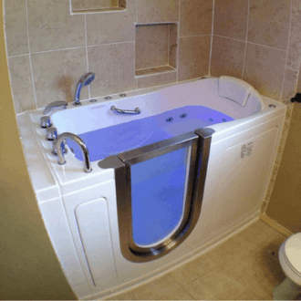 Walk In Tub Reviews Testimonials Feedback 2 White walk-in tub with open door and blue water lighting installed in a beige tiled bathroom with handheld shower