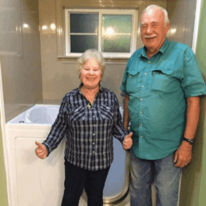 Walk In Tub Reviews Testimonials Feedback 38 Senior couple smiling and giving thumbs up beside their newly installed Ella walk-in tub in a remodeled bathroom
