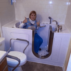 Walk In Tub Reviews Testimonials Feedback 39 Senior woman giving two thumbs up while seated inside an Ella walk-in bathtub showing satisfaction in a tiled bathroom