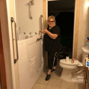 Walk In Tub Reviews Testimonials Feedback 44 Senior woman smiling while opening the door of her Ella walk-in tub in a home bathroom with grab bars