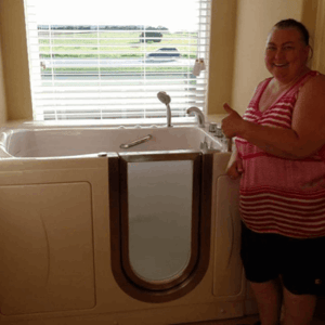 Walk In Tub Reviews Testimonials Feedback 62 Woman giving thumbs up beside her newly installed Ella walk-in tub with outward swing door in bright bathroom