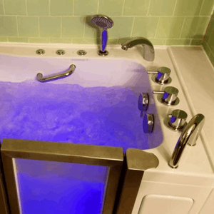 Walk In Tub Reviews Testimonials Feedback 85 Walk-in tub filled with blue chromotherapy-lit water showing chrome faucet controls, handheld shower, and low step-entry door