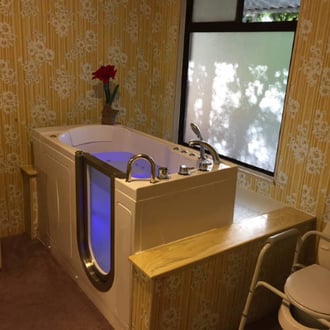 Walk In Tub Reviews Testimonials Feedback Ella walk-in tub with blue chromotherapy lighting and open door installed in a floral-wallpapered home bathroom