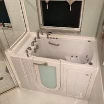White Ella Capri walk-in tub with open door, hydrotherapy jets, chrome faucet set, and interior grab bar installed in a home bathroom