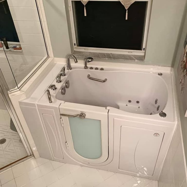 White Ella Capri walk-in tub with open door, hydrotherapy jets, chrome faucet set, and interior grab bar installed in a home bathroom
