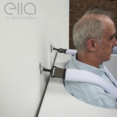 Senior man seated in a walk-in tub using an Ella's Bubbles wall-mounted safety seat belt body strap for secure bathing support