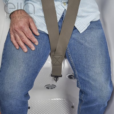 Senior seated in an Ella walk-in tub wearing a safety seat belt strap secured at the center for added bathing support
