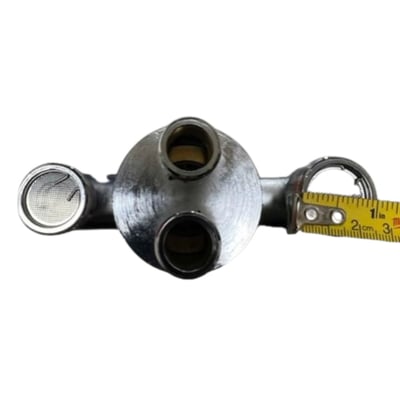 Close-up of a walk-in tub thermostatic control valve body with multiple ports measured by a tape measure
