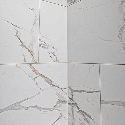 Baldosa machihembrada de PVC Carrara de 25"x15" - Primer plano de paneles de pared de azulejos de clic con aspecto de mármol blanco con vetas grises y doradas en una cabina de ducha accesible