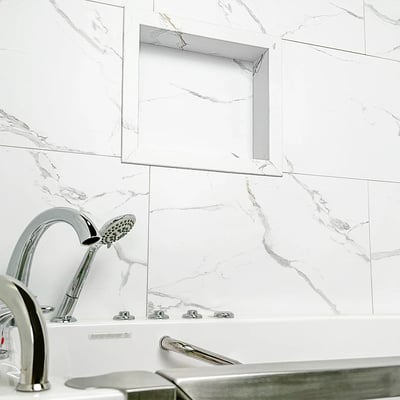 Baldosa machihembrada de PVC Carrara de 25"x15" - Primer plano de una bañera con grifo cromado y chorros frente a paneles de pared de ducha de mármol de Carrara sin lechada con estante de nicho integrado