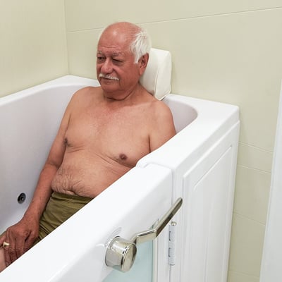 Hombre mayor relajándose en una bañera Ella con soporte de reposacabezas acolchado y puerta de apertura interior cerrada con asa cromada