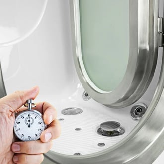 Accueil Hand holding a stopwatch next to an open Ella walk-in tub door highlighting fast drain technology and jet controls