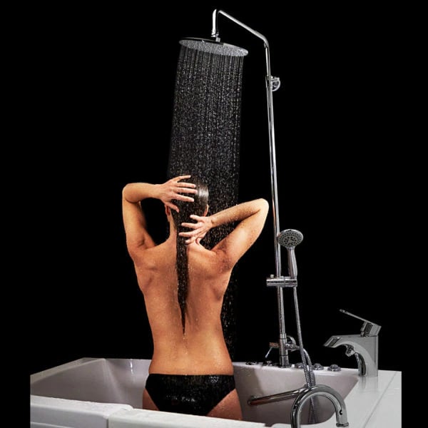 Woman rinsing hair under large rain shower head column with chrome fixtures mounted on a walk-in tub