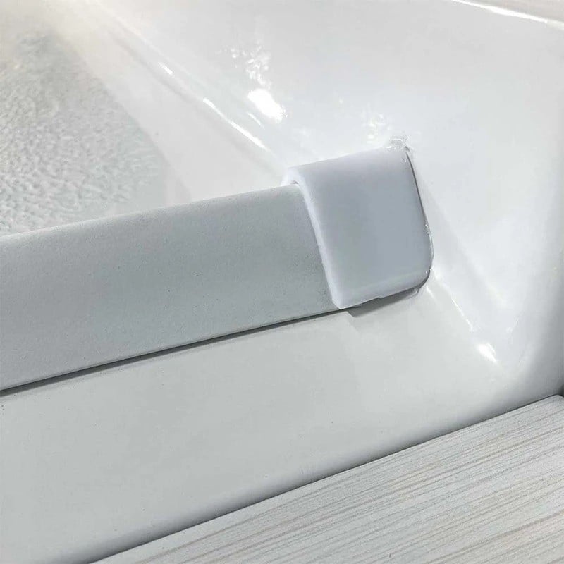 corner-collapsible-dam-shower-base-ellas-bubbles Gros plan d'un barrage de seuil pliable blanc sur une base de douche d'angle Ella's Bubbles pour accès sans obstacle