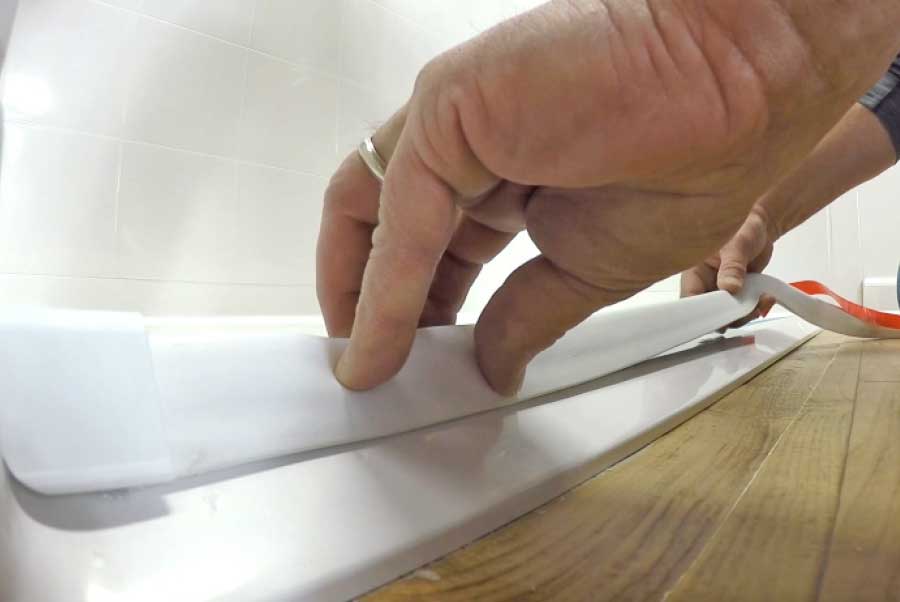 Instalador presionando el tope de ducha flexible blanco contra el umbral de un plato de ducha Ella sin barreras