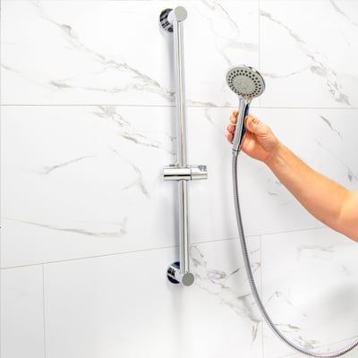 Kit 4 pièces : bras de douche à main et fixation coulissante 24” - Main agrippant une douchette à main chromée sur une barre de douche réglable, montée sur un mur de douche en marbre blanc