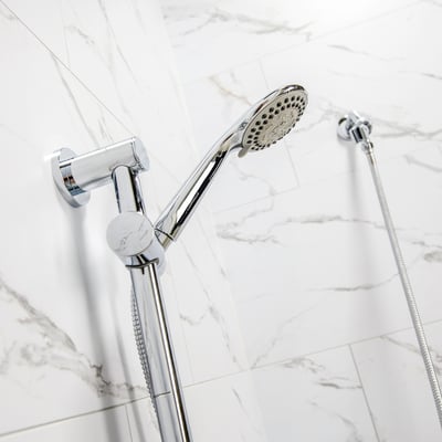 Kit 4 pièces : bras de douche à main et fixation coulissante 24” - Gros plan d’une douchette à main chromée sur une barre de douche réglable, devant du carrelage marbre blanc dans une cabine de douche accessible