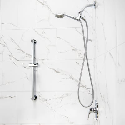 Chrome handheld shower head with flexible hose and adjustable slide bar mounted on white marble shower wall