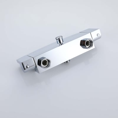 Close-up of a polished chrome thermostatic shower valve with dual water inlet ports and central diverter button
