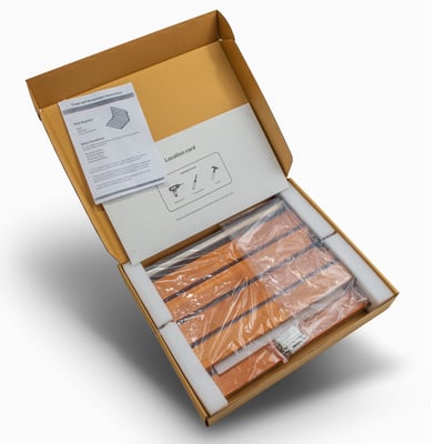 Open box showing a folding shower seat kit with teak wood slats wrapped in plastic and installation instructions