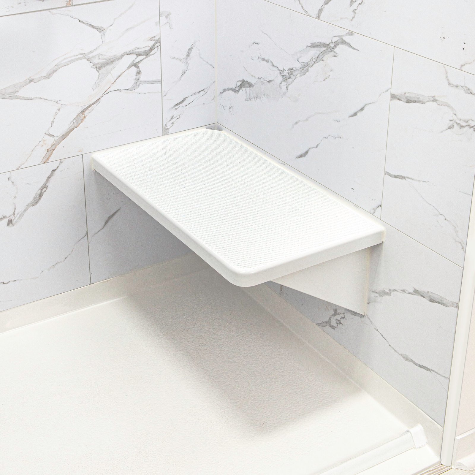 Asiento esquinero abatible blanco para ducha con textura antideslizante, montado en paneles de pared de mármol dentro de una cabina de ducha accesible