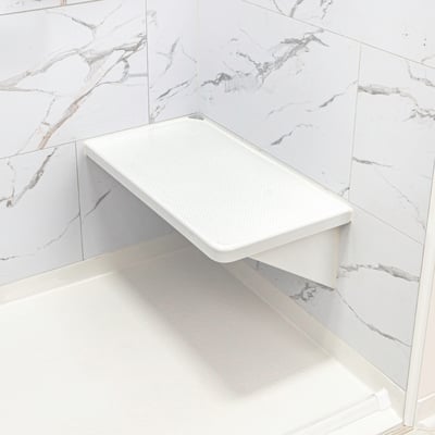 Siège de douche d’angle blanc rabattable avec texture antidérapante, monté sur des panneaux muraux en marbre à l’intérieur d’une cabine de douche accessible