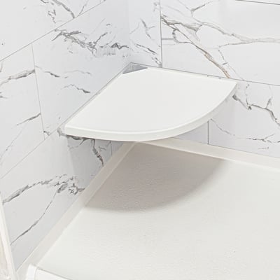 Close-up of a white fold-down corner shower seat mounted in an accessible shower stall with marble-style walls