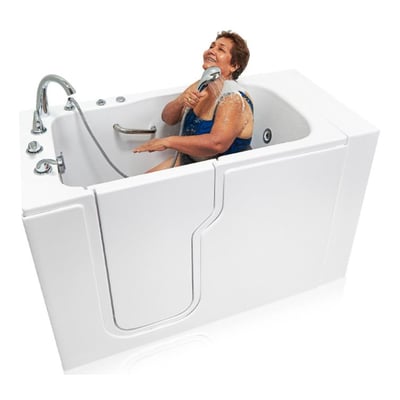 Mujer mayor riendo mientras usa una ducha de mano dentro de la bañera de acceso Ella Standard 30x52 de acrílico con puerta de entrada lateral