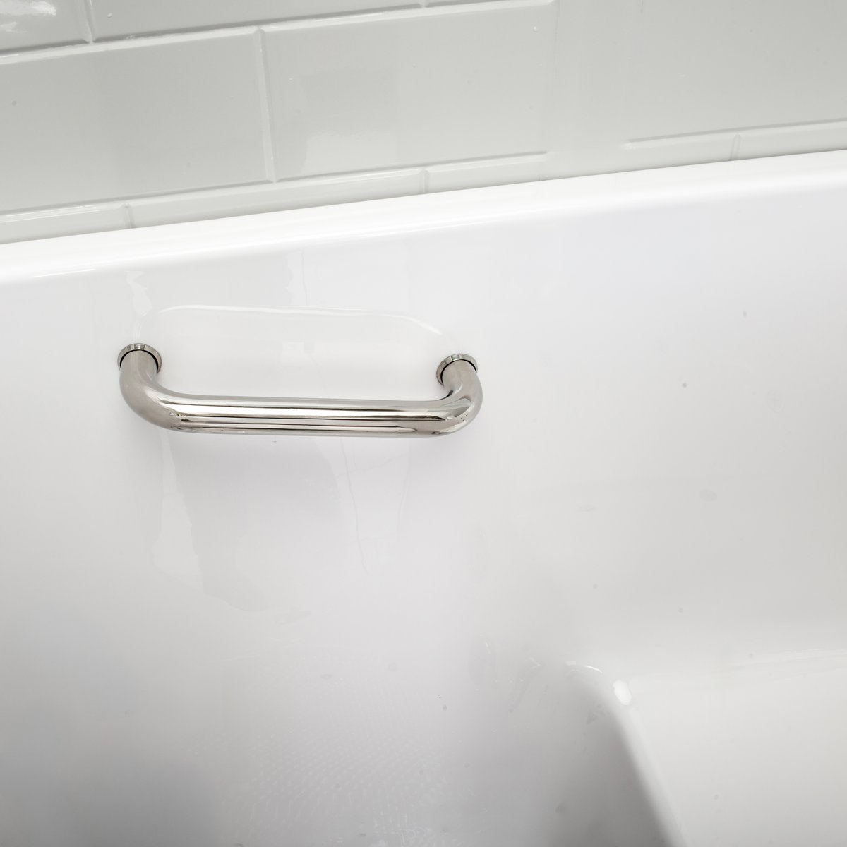 Primer plano de la barra de sujeción de acero inoxidable montada en la cubierta dentro de una bañera con puerta Ella Lounger