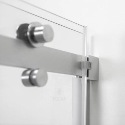 Primer plano de los herrajes de la puerta corredera en acero inoxidable cepillado y panel de vidrio templado transparente en la puerta de cabina de ducha Primo