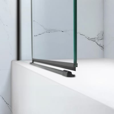 Primer plano del riel inferior negro mate y el panel de cristal transparente de la mampara de bañera plegable sin perfilería Ella Tidy con fondo de pared de mármol
