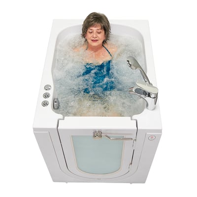 Overhead view of a woman bathing in a white front-entry walk-in tub with microbubble jets and a chrome faucet