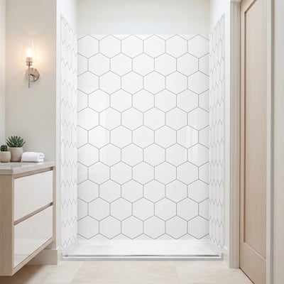 Walk in shower with white hexagon acrylic wall panels beside a light wood door and beige vanity