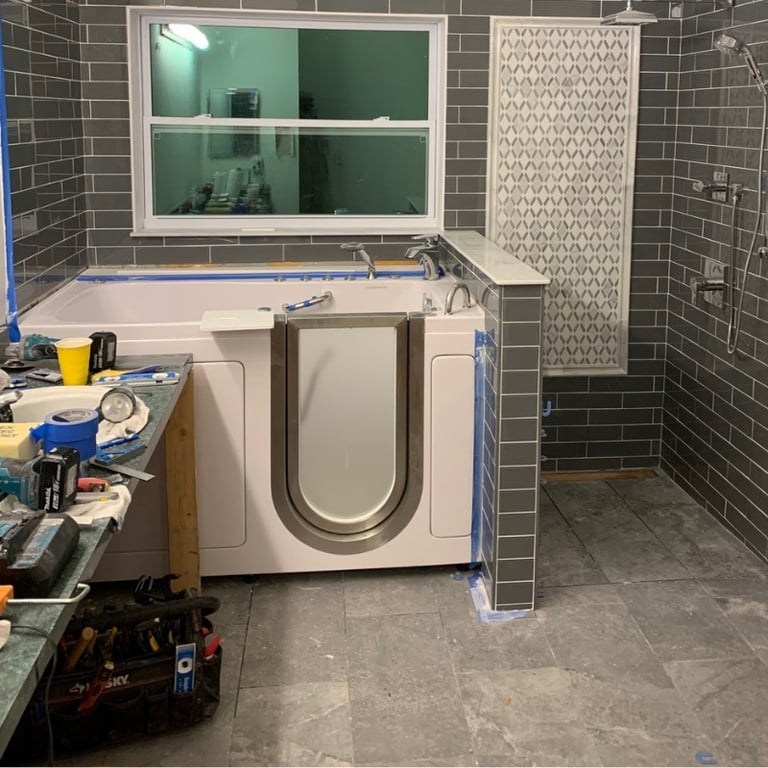 Ella walk-in tub being professionally installed in a tiled bathroom remodel next to an accessible roll-in shower stall