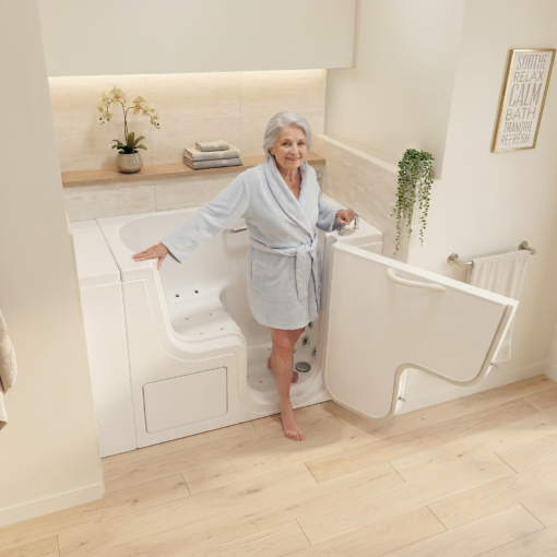 Senior woman in a blue robe stepping through the open door of the Ella Transfer26 ADA accessible walk-in tub