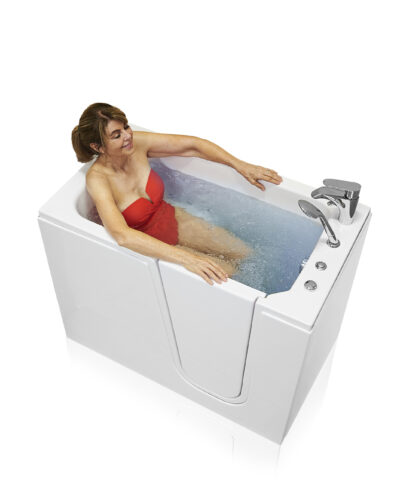 Woman in red swimsuit relaxing in Ella Flow white walk-in tub with hydro jets and side entry door