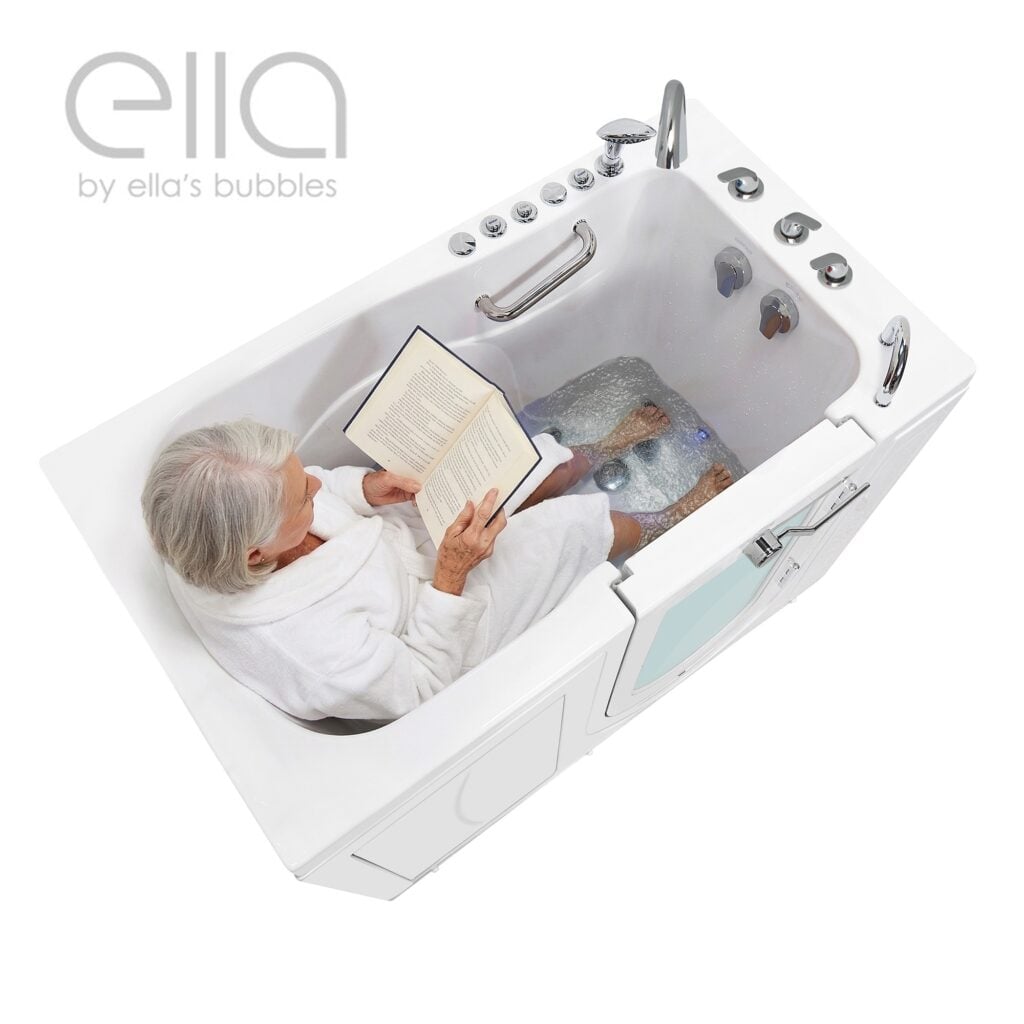 Mujer mayor con albornoz blanco leyendo un libro mientras remoja los pies en la bañera con puerta Ella Monaco con puerta de apertura exterior y chorros de hidromasaje.